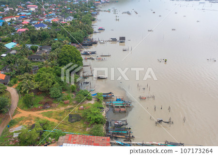 Aerial view of fishing trap net in canel with fisherman urban city village town houses, lake or river. Nature landscape fisheries and fishing tools at Pak Pha, Songkhla, Thailand. Aquaculture farming 107173264
