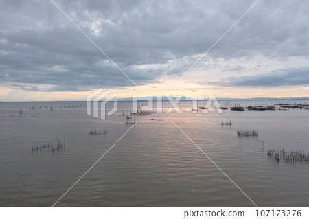 Aerial view of fishing trap net in canel with fisherman urban city village town houses, lake or river. Nature landscape fisheries and fishing tools at Pak Pha, Songkhla, Thailand. Aquaculture farming Aerial view of fishing trap net in canel with fisherman urban city village town houses, lake or river. Nature landscape fisheries and fishing tools at Pak Pha, Songkhla, Thailand. Aquaculture farming 107173276