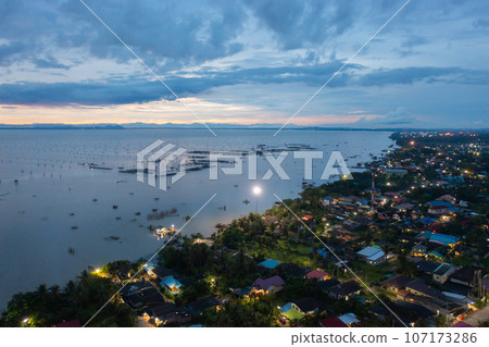Aerial view of fishing trap net in canel with fisherman urban city village town houses, lake or river. Nature landscape fisheries and fishing tools at Pak Pha, Songkhla, Thailand. Aquaculture farming 107173286