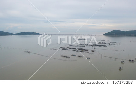 Aerial view of fishing trap net in canel with fisherman urban city village town houses, lake or river. Nature landscape fisheries and fishing tools at Pak Pha, Songkhla, Thailand. Aquaculture farming Aerial view of fishing trap net in canel with fisherman urban city village town houses, lake or river. Nature landscape fisheries and fishing tools at Pak Pha, Songkhla, Thailand. Aquaculture farming 107173298
