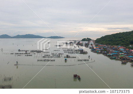 Aerial view of fishing trap net in canel with fisherman urban city village town houses, lake or river. Nature landscape fisheries and fishing tools at Pak Pha, Songkhla, Thailand. Aquaculture farming 107173375
