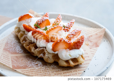 Yummy waffles with whipped cream, strawberries and caramel syrup on table, top view shot 107173469