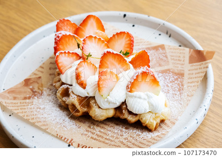 Yummy waffles with whipped cream, strawberries and caramel syrup on table, top view shot Yummy waffles with whipped cream, strawberries and caramel syrup on table, top view shot 107173470