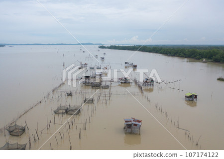 Aerial view of fishing trap net in canel with fisherman urban city village town houses, lake or river. Nature landscape fisheries and fishing tools at Pak Pha, Songkhla, Thailand. Aquaculture farming Aerial view of fishing trap net in canel with fisherman urban city village town houses, lake or river. Nature landscape fisheries and fishing tools at Pak Pha, Songkhla, Thailand. Aquaculture farming 107174122