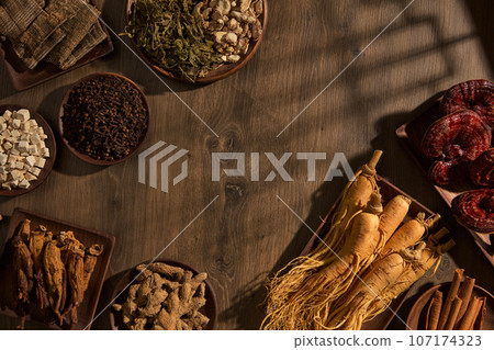 Vintage background with wooden trays filled with traditional medicine: ginseng root, ganoderma, ginger, cinnamon, turmeric,...Blank space for presentation product. Top view, advertising photo 107174323