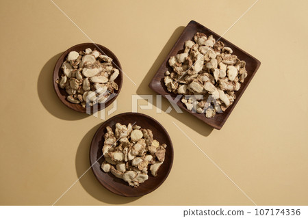 Top view of three wooden trays filled with sand ginger slices decorated on beige background. Photo for medicine advertising. Sand ginger is effective in treating digestive diseases. Top view of three wooden trays filled with sand ginger slices decorated on beige background. Photo for medicine advertising. Sand ginger is effective in treating digestive diseases. 107174336