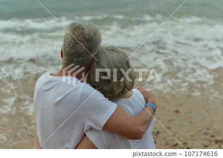 silhouette rear view of asian elderly couple standing on the beach and chatting happily in sunrise silhouette rear view of asian elderly couple standing on the beach and chatting happily in sunrise 107174616