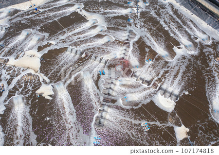 Aerial view of natural sea salt ponds, lake or sea. Farm field outdoor in traditional industry in Thailand. Asia culture. Agriculture irrigation. River reflection. Aerial view of natural sea salt ponds, lake or sea. Farm field outdoor in traditional industry in Thailand. Asia culture. Agriculture irrigation. River reflection. 107174818