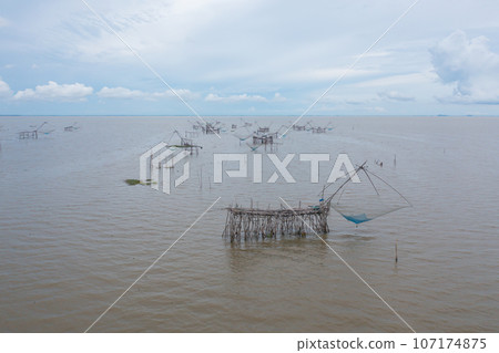 Aerial view of fishing trap net in canel with fisherman urban city village town houses, lake or river. Nature landscape fisheries and fishing tools at Pak Pha, Songkhla, Thailand. Aquaculture farming Aerial view of fishing trap net in canel with fisherman urban city village town houses, lake or river. Nature landscape fisheries and fishing tools at Pak Pha, Songkhla, Thailand. Aquaculture farming 107174875