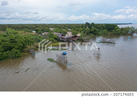 Aerial view of fishing trap net in canel with fisherman urban city village town houses, lake or river. Nature landscape fisheries and fishing tools at Pak Pha, Songkhla, Thailand. Aquaculture farming Aerial view of fishing trap net in canel with fisherman urban city village town houses, lake or river. Nature landscape fisheries and fishing tools at Pak Pha, Songkhla, Thailand. Aquaculture farming 107174883