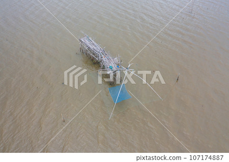 Aerial view of fishing trap net in canel with fisherman urban city village town houses, lake or river. Nature landscape fisheries and fishing tools at Pak Pha, Songkhla, Thailand. Aquaculture farming 107174887