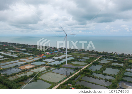 Aerial view of wind turbines or windmills farm field and sea shore beach in industry factory. water power, sustainable green clean energy, and environment concept. Nature innovation. Aerial view of wind turbines or windmills farm field and sea shore beach in industry factory. water power, sustainable green clean energy, and environment concept. Nature innovation. 107174993