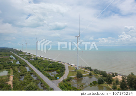 Aerial view of wind turbines or windmills farm field and sea shore beach in industry factory. water power, sustainable green clean energy, and environment concept. Nature innovation. Aerial view of wind turbines or windmills farm field and sea shore beach in industry factory. water power, sustainable green clean energy, and environment concept. Nature innovation. 107175254