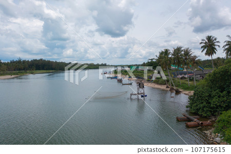 Aerial view of fishing trap net in canel with fisherman urban city village town houses, lake or river. Nature landscape fisheries and fishing tools at Pak Pha, Songkhla, Thailand. Aquaculture farming Aerial view of fishing trap net in canel with fisherman urban city village town houses, lake or river. Nature landscape fisheries and fishing tools at Pak Pha, Songkhla, Thailand. Aquaculture farming 107175615