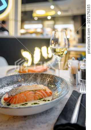 Salmon fillet in cream sauce with herbs on a marble table in a restaurant 107176285