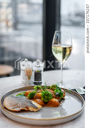 Sea bass or dorado fillet with baked potatoes and cauliflower on a gray plate Sea bass or dorado fillet with baked potatoes and cauliflower on a gray plate 107176287