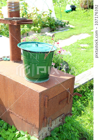 A metal bucket stands on a homemade cast iron stove in the garden 107176392