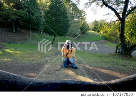 A man squats down and takes a photo with a single-lens reflex camera A man squats down and takes a photo with a single-lens reflex camera 107177030