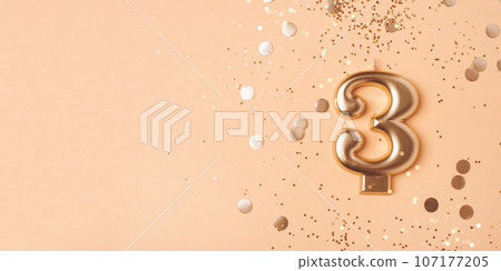 Gold candle in the form of number three. 107177205