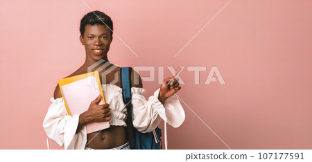 Smiling transgender student with notebooks pointing away Smiling transgender student with notebooks pointing away 107177591