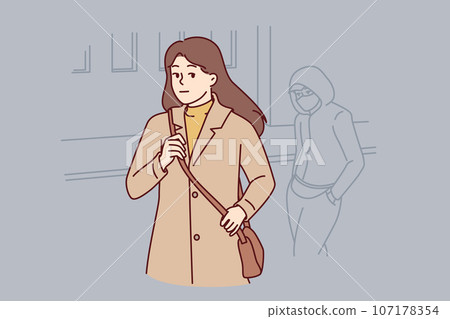 Woman walking through city at night notices stalker who wants to attack or rob defenseless girl 107178354