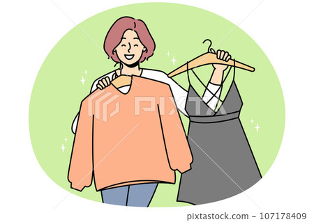Smiling woman holding clothes on hangers 107178409