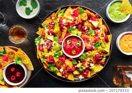 Loaded nachos. Mexican nacho chips with beef, overhead flat lay shot 107178533