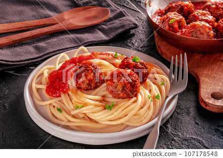 Meatballs. Beef meat balls, n a pan and with a plate of spaghetti pasta 107178548