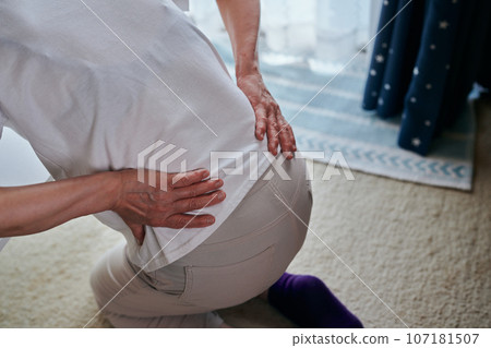 Senior woman standing up while fighting back pain 107181507