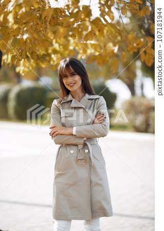 Girl in a brown coat. Woman in a autumn park. Lady with a leaf. Girl in a brown coat. Woman in a autumn park. Lady with a leaf. 107181944