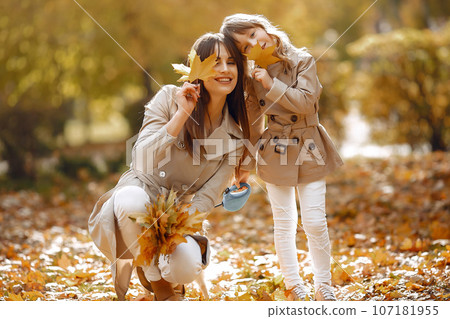 Fashionable mother with daughter. Family in a autumn park. Family with a dog. Fashionable mother with daughter. Family in a autumn park. Family with a dog. 107181955