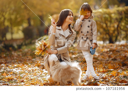 Fashionable mother with daughter. Family in a autumn park. Family with a dog. Fashionable mother with daughter. Family in a autumn park. Family with a dog. 107181956