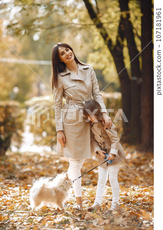 Fashionable mother with daughter. Family in a autumn park. Family with a dog. Fashionable mother with daughter. Family in a autumn park. Family with a dog. 107181961