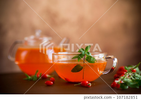 Prepared drink from ripe goji berries in a glass cup and teapot 107182851