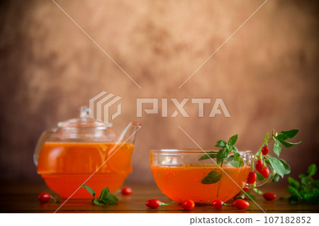 Prepared drink from ripe goji berries in a glass cup and teapot Prepared drink from ripe goji berries in a glass cup and teapot 107182852