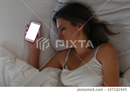 Smartphone is lying in womans hand while she sleeping Smartphone is lying in womans hand while she sleeping 107182945