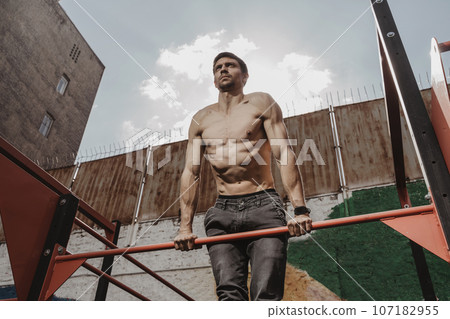 Shirtless athlete practicing calisthenics with smartwatch on his wrist. Shirtless athlete practicing calisthenics with smartwatch on his wrist. 107182955