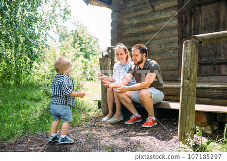 Mom, dad and little son spend time together in the summer outdoors 107185297
