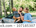 Mom, dad and little son in a convertible car. Summer family road trip to nature 107185307