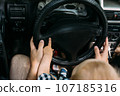 Dad shows his little son how to drive car while sitting behind wheel 107185316