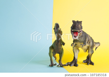 2 dinosaurs fighting on a yellow and blue background 2 dinosaurs fighting on a yellow and blue background 107185318