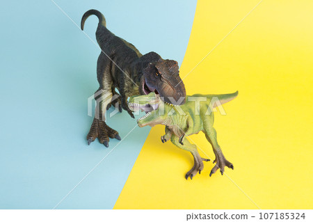2 dinosaurs fighting on a yellow and blue background 107185324