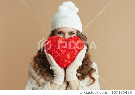 elegant woman in beige sweater, mittens and hat on beige elegant woman in beige sweater, mittens and hat on beige 107185459