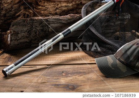 Butt of a fishing rod on a wooden stump. Camouflage fisherman's cap. Fishing screensaver. Butt of a fishing rod on a wooden stump. Camouflage fisherman's cap. Fishing screensaver. 107186939