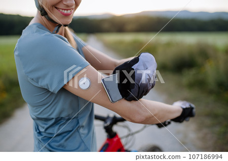Diabetic cyclist connecting continuous glucose monitor with her smartphone to monitor her blood sugar levels in real time. 107186994