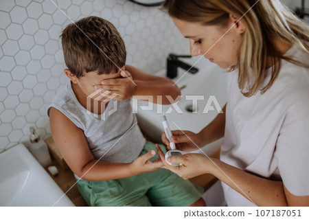 Mother checking her son's blood glucose level at home using a fingerstick glucose meter. Mother checking her son's blood glucose level at home using a fingerstick glucose meter. 107187051