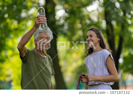 The senior man drinking water during workout. The senior man drinking water during workout. 107187132