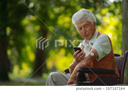 Senior diabetic man checking his glucose data on smartphone outdoors, in park. Senior diabetic man checking his glucose data on smartphone outdoors, in park. 107187164