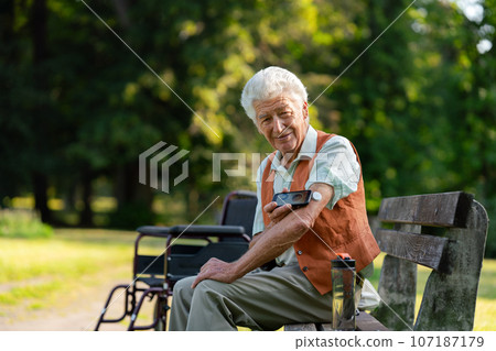 Senior diabetic man checking his glucose data on smartphone outdoors, in park. Senior diabetic man checking his glucose data on smartphone outdoors, in park. 107187179