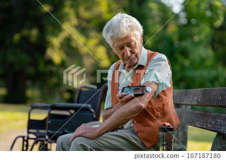Senior diabetic man checking his glucose data on smartphone outdoors, in park. Senior diabetic man checking his glucose data on smartphone outdoors, in park. 107187180